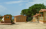 Row of bungalows and trees at Camping Rocagrossa Bungalow for 4 people in Spain on a clear day.