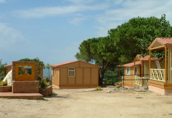 Row of bungalows and trees at Camping Rocagrossa Bungalow for 4 people in Spain on a clear day.