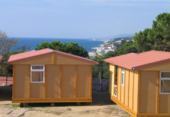 Camping Rocagrossa bungalows for 4 people in Spain overlooking the sea, beach and green pine trees on the coast.