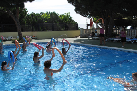 Persone partecipano all'acquagym con tubi galleggianti in una piscina esterna presso un alloggio glamping.