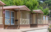 Wooden bungalow for 5 people at Camping Rocagrossa in Spain, surrounded by greenery and trees.