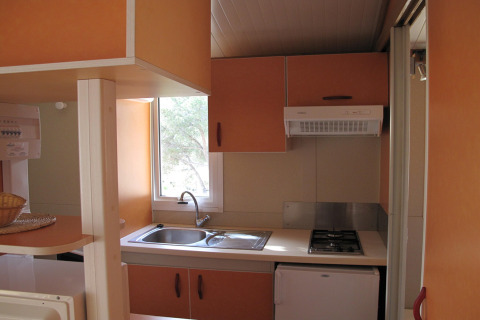 Lille køkkenområde i Camping Rocagrossa Bungalow til 4 personer i Spanien med vask, komfur og skabe.