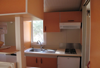 Lille køkkenområde i Camping Rocagrossa Bungalow til 4 personer i Spanien med vask, komfur og skabe.