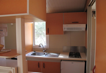 Compact kitchen area in Camping Rocagrossa Bungalow for 4 people in Spain, featuring a sink and stove.