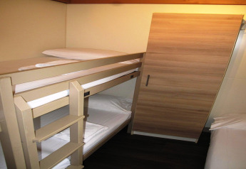 Photo of a room with bunk beds and a wardrobe at Camping Rocagrossa Bungalow for 4 people in Spain.