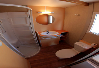 Bathroom at Camping Rocagrossa Bungalow for 4 people in Spain featuring a shower, toilet, and sink.