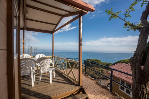 Overdækket terrasse med plastikstole og havudsigt på Camping Rocagrossa Bungalow 4 personer i Spanien.