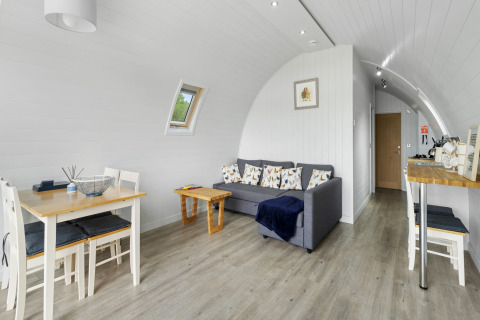 Lichte, moderne woonkamer in de pod The Chicken Coop met eettafel, bank en houten accenten in het VK.