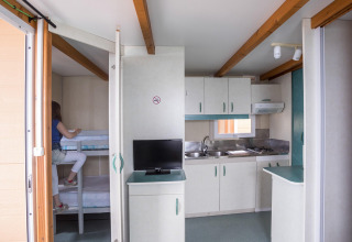 Indvendigt billede af Camping Rocagrossa Bungalow i Spanien med tekøkken, tv og køjesenge.