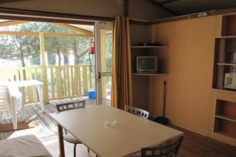 Indvendigt billede af en bungalow ved Camping Rocagrossa i Spanien, med spisebord og åben terrasse.