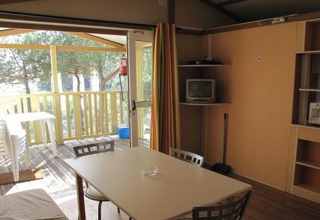 Indvendigt billede af en bungalow ved Camping Rocagrossa i Spanien, med spisebord og åben terrasse.