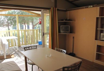 Interior of a bungalow at Camping Rocagrossa in Spain, showing table, chairs, and access to outdoor terrace.