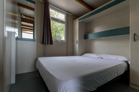 Soveværelse med dobbeltseng og moderne indretning i Camping Rocagrossa Bungalow for 5 personer i Spanien.
