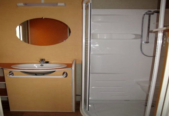Salle de bain du Camping Rocagrossa Bungalow en Espagne, avec lavabo, miroir et douche moderne.