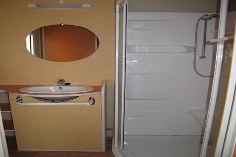 Badeværelse i Camping Rocagrossa Bungalow i Spanien, med vask, spejl og moderne brusekabine.