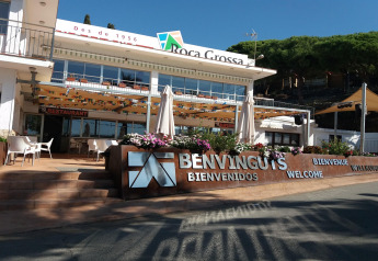 Foto dell'alloggio glamping Roca Grossa con insegna di benvenuto, ristorante e terrazza soleggiata.
