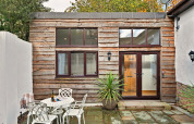 Esterno della cabina Hillfarrow Hideaway nel Regno Unito con rivestimento in legno e tavolo da patio.