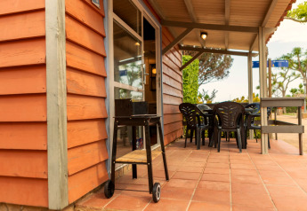 Terrasse des Camping del Mar BUNGALOW MEDITERRANI in Spanien mit Grill, Tisch und Stühlen.