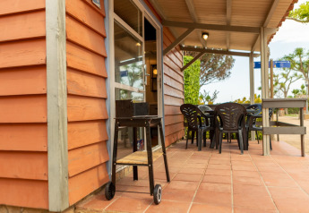 Outdoor patio at Camping del Mar BUNGALOW MEDITERRANI, Spain, with barbecue, table and chairs.