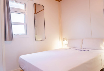 Bright bedroom at Camping del Mar Bungalow Mediterrani in Spain, featuring a double bed, window, and mirror.