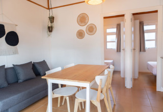 Heldere en gezellige woonkamer met eettafel en bank bij Camping del Mar BUNGALOW MEDITERRANI in Spanje.