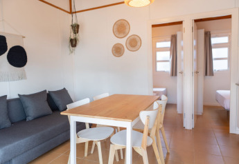 Bright cozy living room at Camping del Mar BUNGALOW MEDITERRANI in Spain with dining table and sofa.