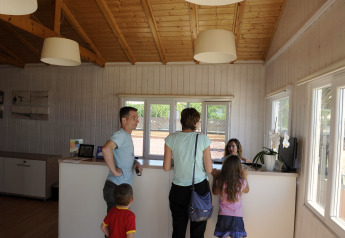 Familie checkt an der Rezeption einer Glamping-Unterkunft mit Holzdecke und freundlicher Atmosphäre ein.