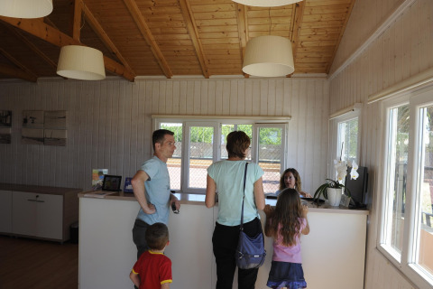 Gezin checkt in bij de receptie van een glamping accommodatie met houten wanden en een gezellige sfeer.