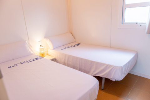 Twee eenpersoonsbedden in een lichte kamer bij Camping del Mar BUNGALOW MEDITERRANI in Spanje, met raam.