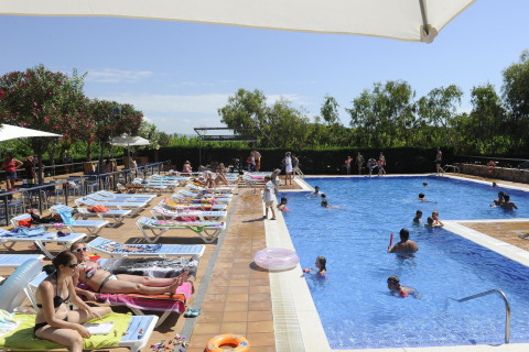 Buitenzwembad bij Camping del Mar BUNGALOW MEDITERRANI in Spanje, met gasten op ligstoelen en in het water.