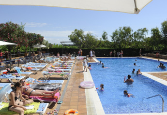 Outdoor swimming pool at Camping del Mar BUNGALOW MEDITERRANI in Spain, with guests relaxing and swimming.