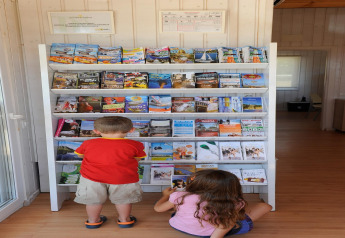Two children browsing brochures at an information rack in Camping del Mar BUNGALOW MEDITERRANI, Spain.