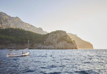 Scenic view of a boat on the sea with mountains behind, near Camping del Mar BUNGALOW MEDITERRANI in Spain.