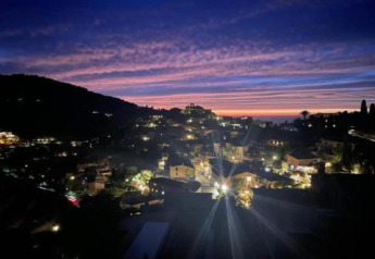 Evening view from Camping del Mar BUNGALOW MEDITERRANI in Spain, showing lit town and colorful sunset sky.
