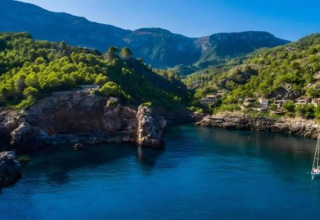 Prachtig kustuitzicht vanaf Camping del Mar BUNGALOW MEDITERRANI in Spanje met groene heuvels en blauw water.