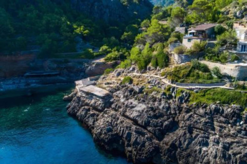 Rotsachtige kustlijn met groen en huizen bij Camping del Mar BUNGALOW MEDITERRANI in Spanje.