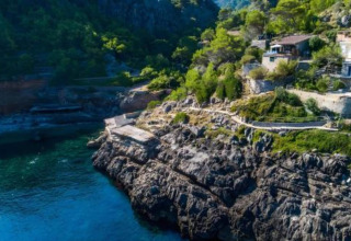 Rotsachtige kustlijn met groen en huizen bij Camping del Mar BUNGALOW MEDITERRANI in Spanje.
