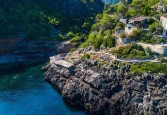 Rocky coastline and greenery with houses near Camping del Mar BUNGALOW MEDITERRANI lodge in Spain.
