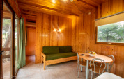 Knusse woonkamer van Vilanova Park BUNGALOW 4 PAX S150 met houten muren, bank en eettafel in Spanje.