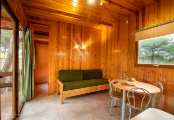Knusse woonkamer van Vilanova Park BUNGALOW 4 PAX S150 met houten muren, bank en eettafel in Spanje.