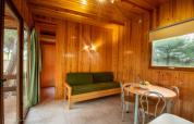 Gemütlicher Wohnbereich im Vilanova Park BUNGALOW 4 PAX S150 mit Holzvertäfelung, Sofa und Esstisch.