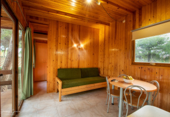 Sala del Vilanova Park BUNGALOW 4 PAX S150 en España, decorada con paredes de madera y muebles básicos.