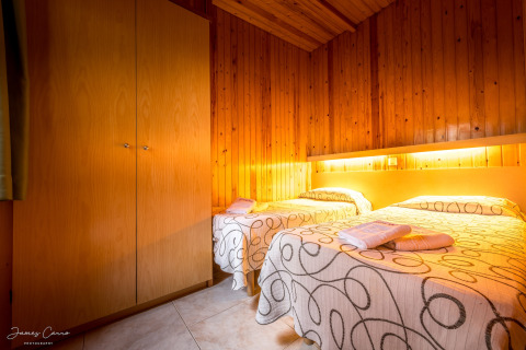 Dormitorio acogedor en Vilanova Park BUNGALOW 4 PAX S150, España, con dos camas y paredes de madera.