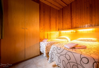 Dormitorio acogedor en Vilanova Park BUNGALOW 4 PAX S150, España, con dos camas y paredes de madera.