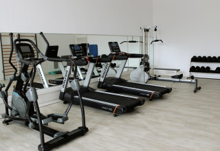 Gimnasio moderno en glamping con cintas de correr, pesas y espejos en una sala luminosa y amplia.