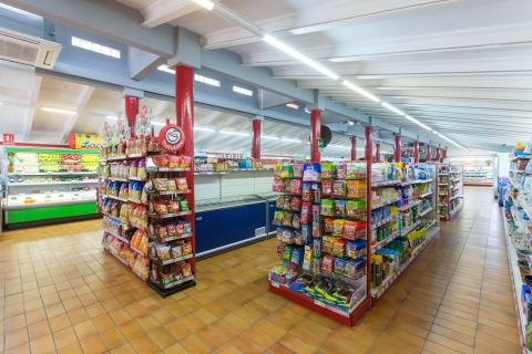 Imagen del interior de un supermercado bien iluminado con pasillos llenos en un alojamiento glamping.