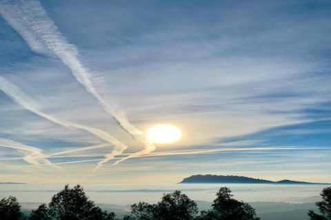 Amanecer con estelas de aviones y montañas visto desde Vilanova Park BUNGALOW 4 PAX S150 en España.