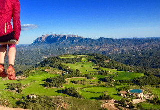 Persona sentada en un columpio con vistas a campos verdes y montañas en Vilanova Park BUNGALOW 4 PAX S150, España.