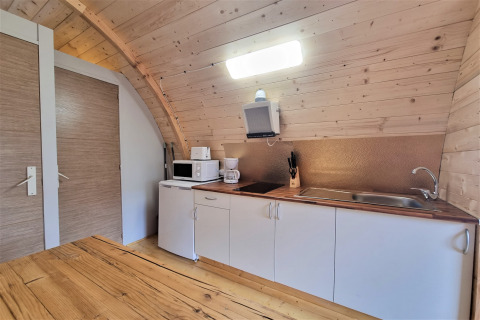 Kitchen in Nomad Paraiso pod in Spain, featuring wood walls, white cabinets, and modern appliances.