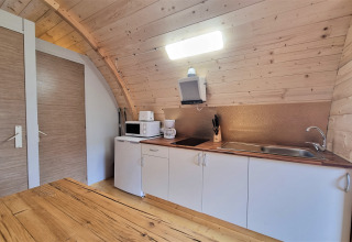 Kitchen in Nomad Paraiso pod in Spain, featuring wood walls, white cabinets, and modern appliances.